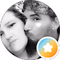 Black and white close-up photo of a woman and man facing the camera, man kissing woman's cheek.